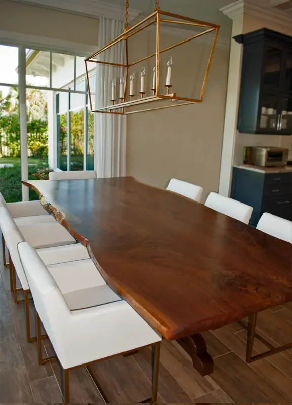 Custom black walnut dining table surrounded by white chairs